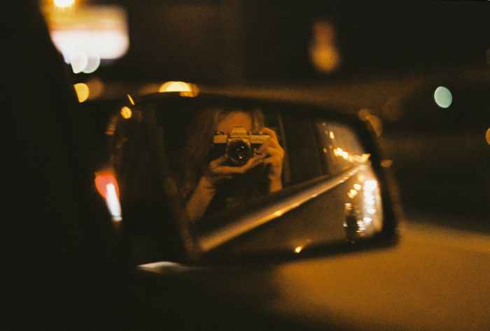 person taking a self portrait on a rear view mirror